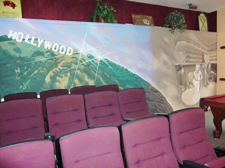 Hollywood themed mural in home cinema with sepia film star portraits. 
