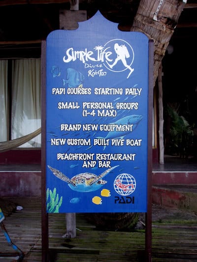 Hand painted sign with turtle, tropical fish and dive shop logos. 