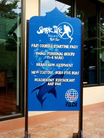 Hand painted sign with whale shark and dive shop logos.